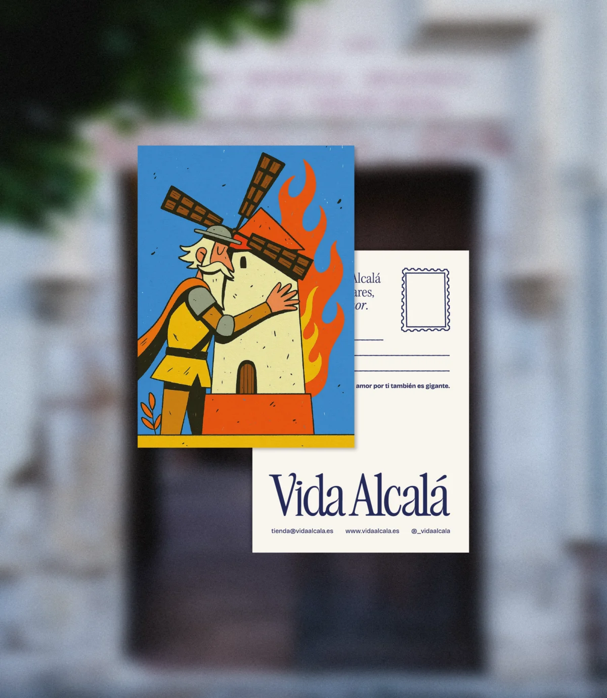 Postal ilustrada con un caballero abrazando un molino en llamas en tonos vivos; deja libre el reverso para tu mensaje personal.