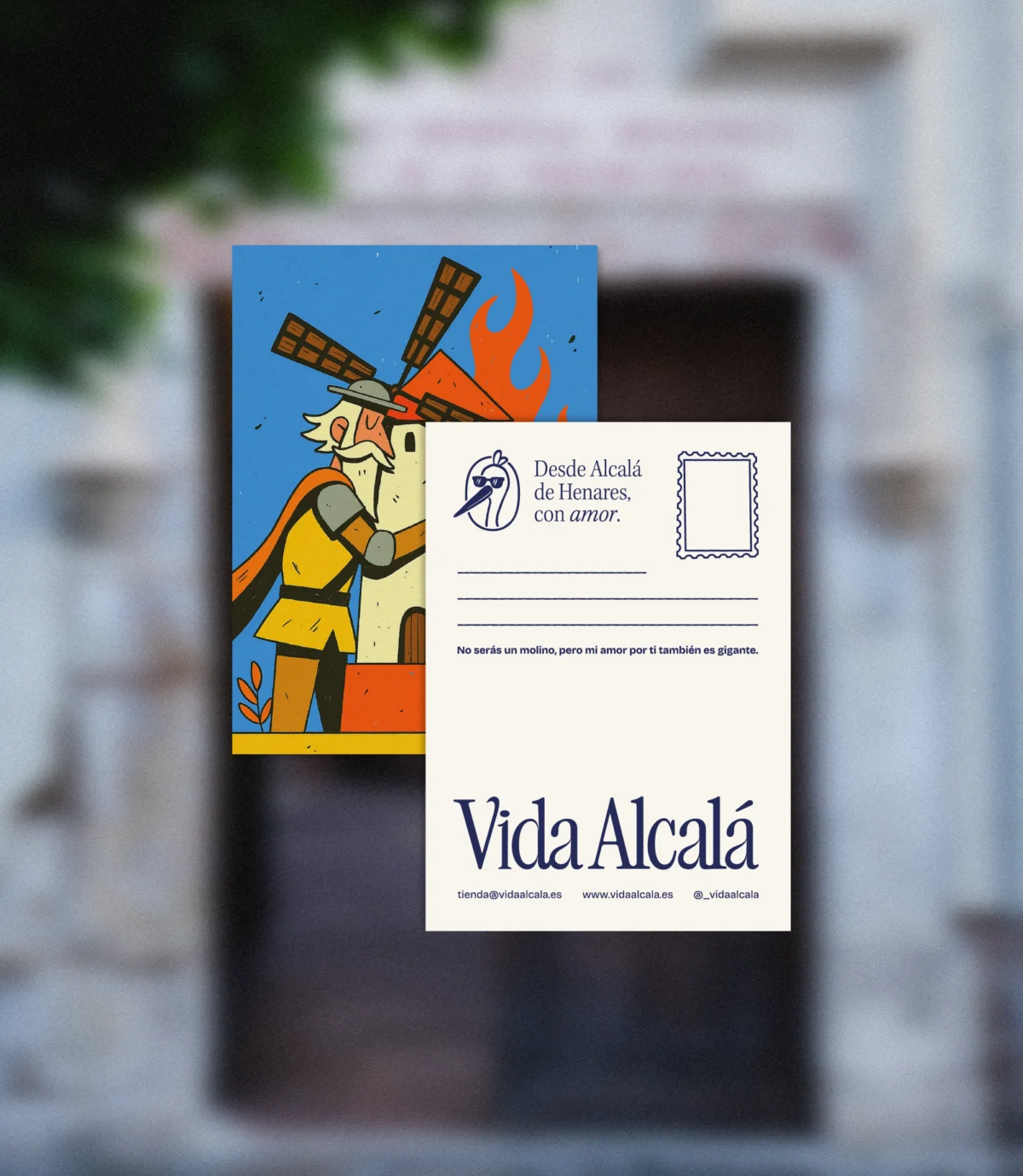 Postal ilustrada con un caballero abrazando un molino en llamas en tonos vivos; deja libre el reverso para tu mensaje personal.